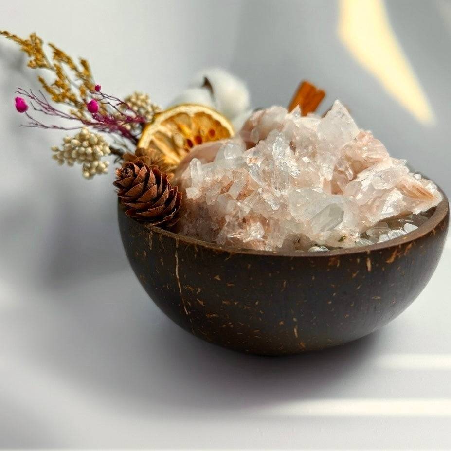 pale pink Lemurian crystal chips in a coconut bowl with cotton, cinnamon and dried flowers in warm natural light