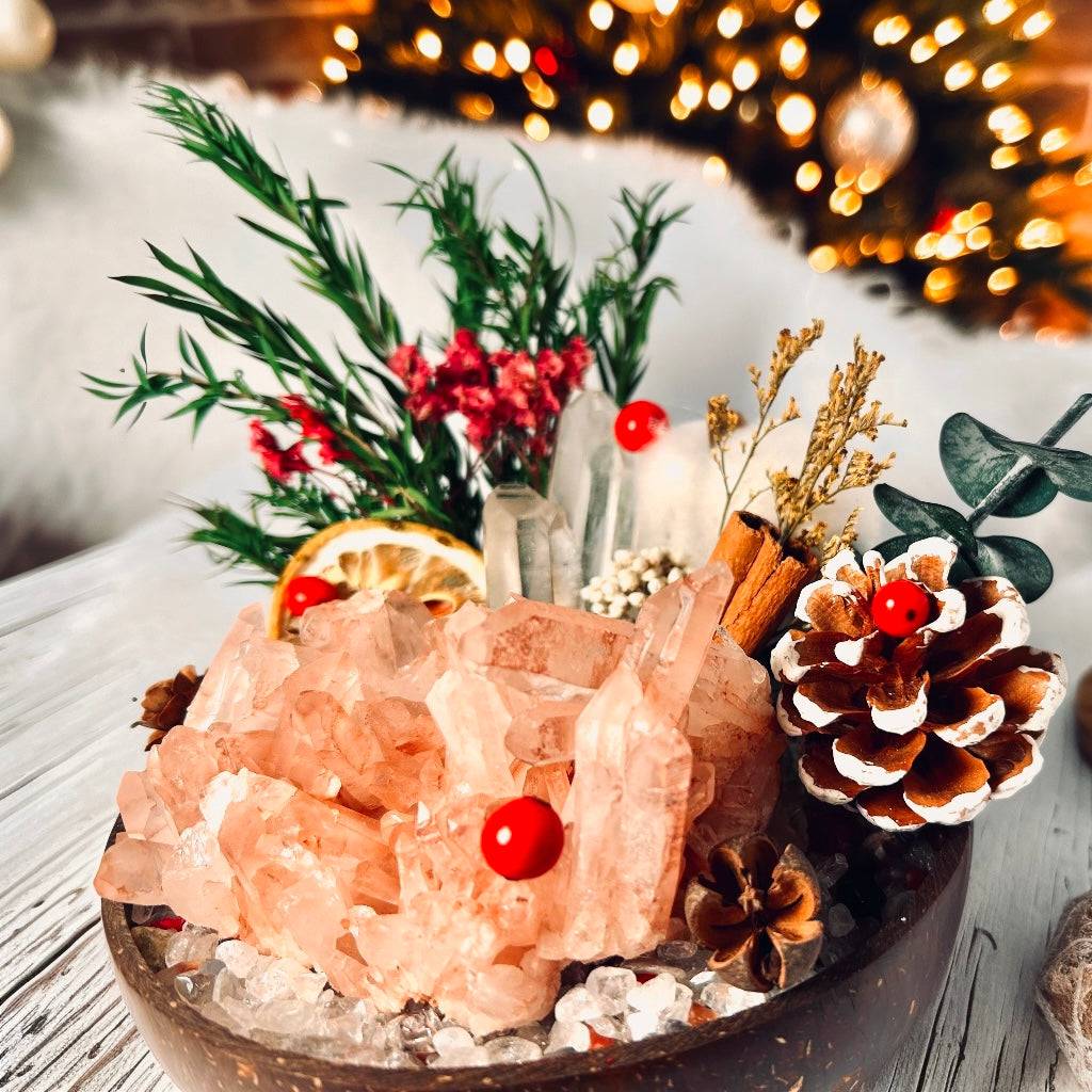 close up of rose quartz crystal cluster mini garden in a coconut bowl with pinecone, dried orange and festive greenery, cozy Christmas crystal gift decor